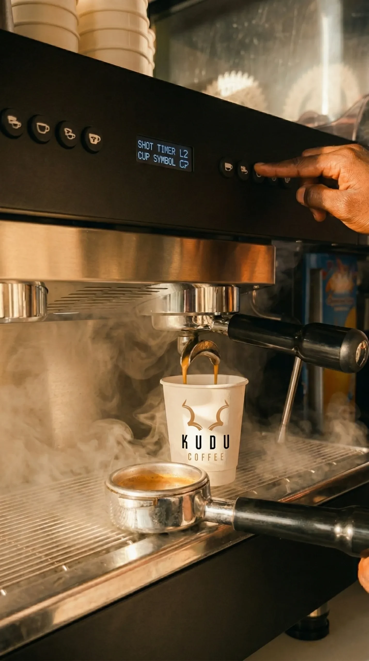 KUDU coffee barista making coffee in a white KUDU coffee branded takeaway cup